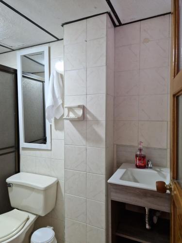 biała łazienka z toaletą i umywalką w obiekcie Habitación baño privado garaje moto, Manizales w mieście Manizales