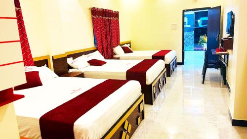 a hotel room with three beds and a television at Hotel SONIA MAHI INN KANYAKUMARI in Kanyakumari