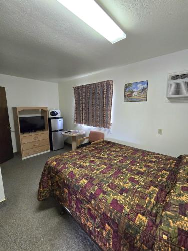 a hotel room with a bed and a television at Dove Creek Inn in Dove Creek