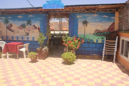 a patio with a table and chairs and a mural at Auberge Restaurant Rooftop Tamazirt in Boumalne
