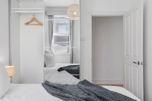a bedroom with a white bed and a mirror at Portside by Property Mums in Melbourne