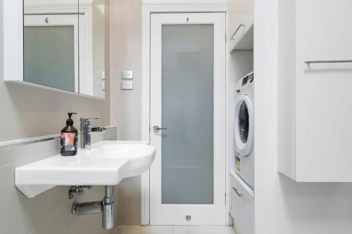 a white bathroom with a sink and a washing machine at Portside by Property Mums in Melbourne