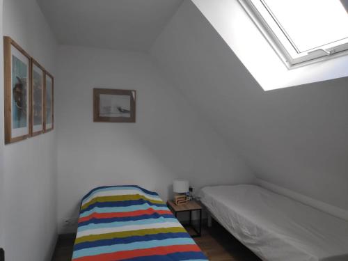 - une petite chambre avec un lit et une lucarne dans l'établissement Gîte au fil de l eau, à Bricquebec