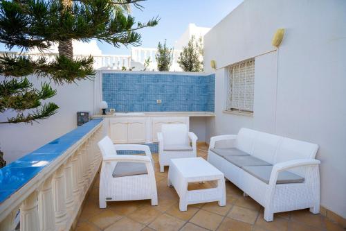 a patio with chairs and a couch and a table at Villa Demoiselle in Zarzis