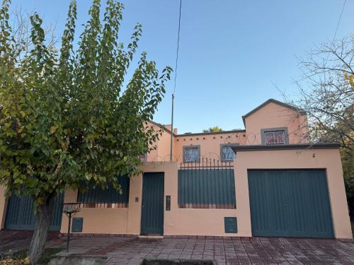 Un edificio con puertas de garaje verdes y un árbol. en Duplex Paraiso, en Villa Nueva