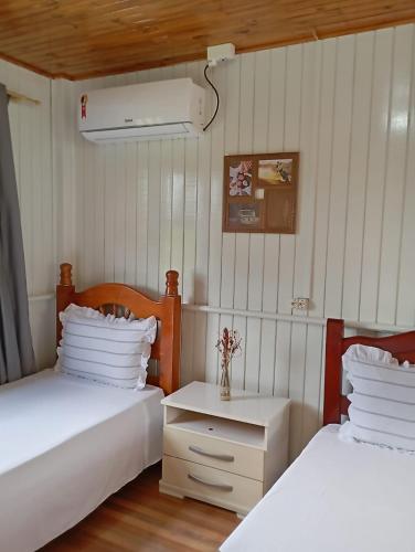 two beds in a room with white walls and wooden floors at Pousada 4 Estações in Louro Müller