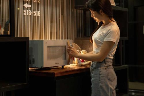 a woman is standing in front of a microwave at Hotel Moon Cheonan ShinBuldang in Cheonan