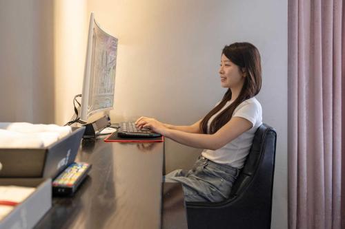a woman sitting at a desk with a computer at Hotel Moon Cheonan ShinBuldang in Cheonan