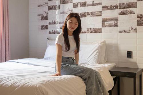 a woman sitting on top of a bed at Hotel Moon Cheonan ShinBuldang in Cheonan