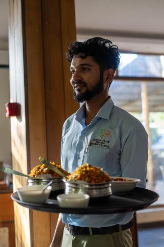 a man holding a tray with food on it at Roys Villa Havelock in Havelock Island