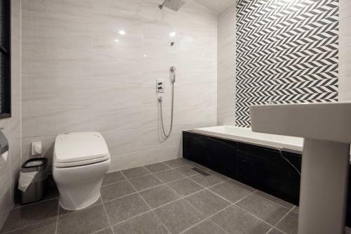 a white bathroom with a toilet and a bath tub at Hotel Moon Cheonan ShinBuldang in Cheonan