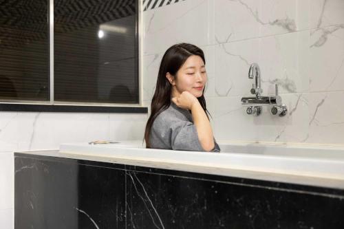 a woman sitting in a sink in a bathroom at Hotel Moon Cheonan ShinBuldang in Cheonan