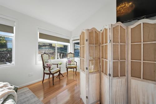 a living room with wooden cabinets and a table and chairs at Blossoms on the Bay - 4 Bedrooms in Nubeena