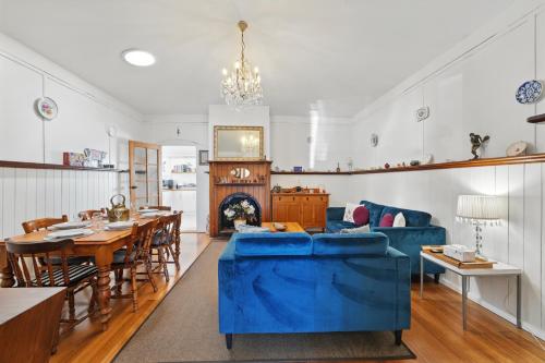 a living room with a blue couch and a table at Blossoms on the Bay - 4 Bedrooms in Nubeena