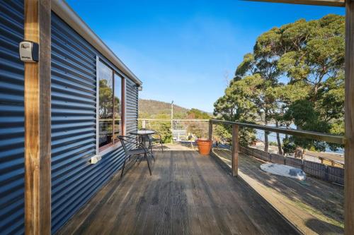 a deck with a table and chairs on a house at Blossoms on the Bay - 4 Bedrooms in Nubeena