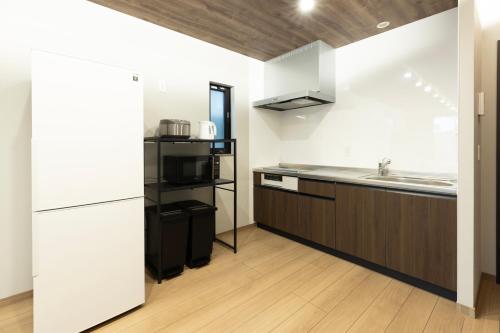 a kitchen with a white refrigerator and a sink at 新築戸建別荘 M&Z house2 in Fukuoka