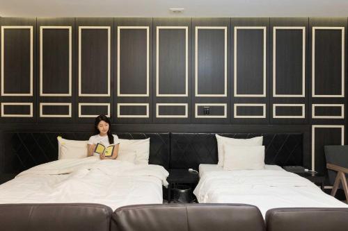 a woman is sitting in between two beds at Hotel Moon Cheonan ShinBuldang in Cheonan