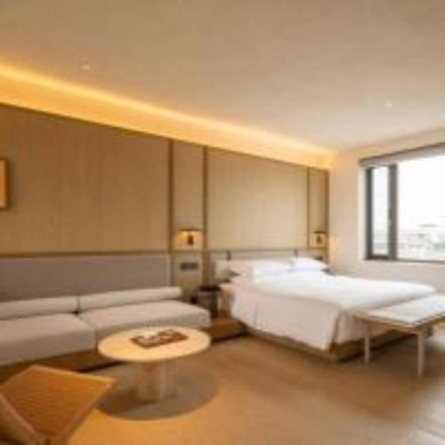 Un dormitorio con una cama, un sofá y una mesa. en 扬州广陵有熊酒店, en Yangzhou