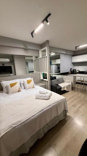 a bedroom with a large bed and a living room at Studio Lifespace Batel Torre A in Curitiba