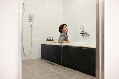 a woman sitting in a bath tub in a bathroom at Hotel Moon Cheonan ShinBuldang in Cheonan