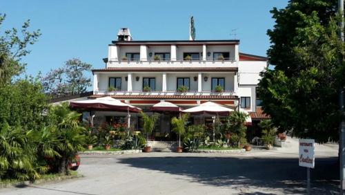 a large white building with umbrellas in front of it at Hotel Ai Sette Nani in Sistiana