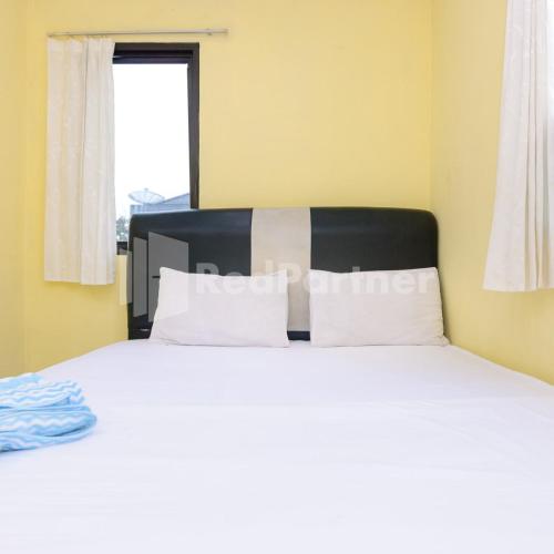 a bedroom with a bed with white sheets and a window at Wisma 24 at Hankam Puncak RedPartner in Kopo 2