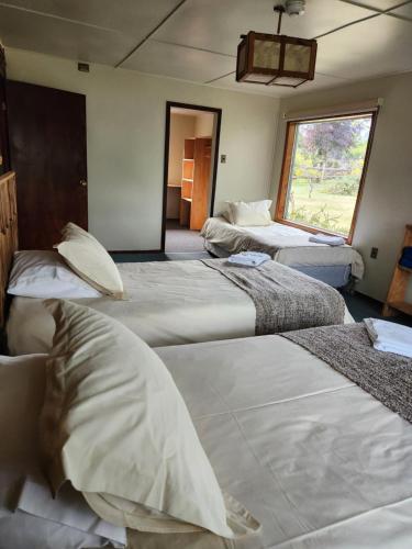 a room with three beds and a window at Casa Bordemar in Castro