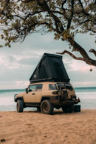 a tan jeep parked on a beach with a tree at Fully Decked All Tan FJ Cruiser! in Kapaa