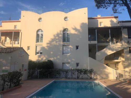 un immeuble avec une piscine devant un immeuble dans l'établissement Appartement 4/5 pers. face à la pinède avec terrasse - FR-1-837-13, à Argelès-sur-Mer