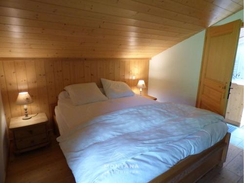 une chambre avec un grand lit dans une pièce en bois dans l'établissement Duplex 4 pièces + mezzanine pour 8 personnes au Grand-Bornand - FR-1-458-227, au Grand-Bornand