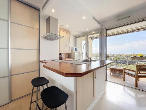 une cuisine avec un comptoir, des tabourets et une fenêtre dans l'établissement Studio lumineux à Antibes avec piscine, tennis et balcon - FR-1-789-10, à Antibes