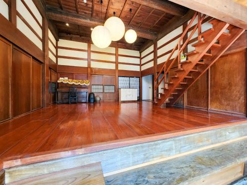 a large room with a wooden floor and stairs at タイピーハウス in Sado