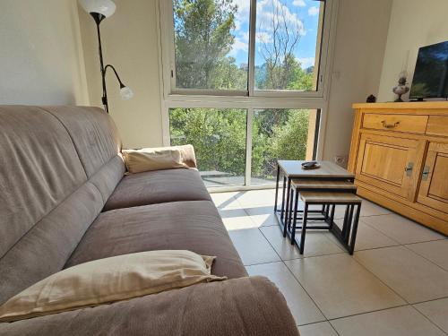 un salon avec un canapé, une table et une fenêtre dans l'établissement Banyuls-sur-Mer: Appartement pour 5 pers. avec terrasse, calme et parking sécurisé - FR-1-309-516, à Banyuls-sur-Mer