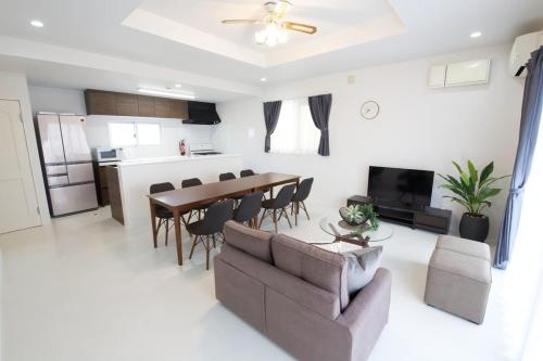 a living room with a table and chairs and a kitchen at プラジールヤカ in Yaka