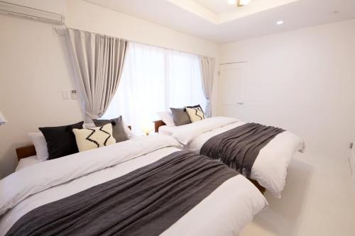 two beds in a room with a window at プラジールヤカ in Yaka