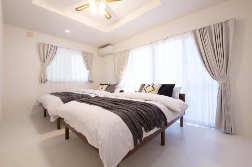 two beds in a white room with windows at プラジールヤカ in Yaka