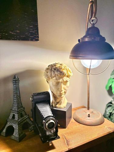 a desk with a lamp and a camera and a statue at Stylish Downtown Condo near Rogers Place l Parking, Gym, Balcony & Kitchen in Edmonton