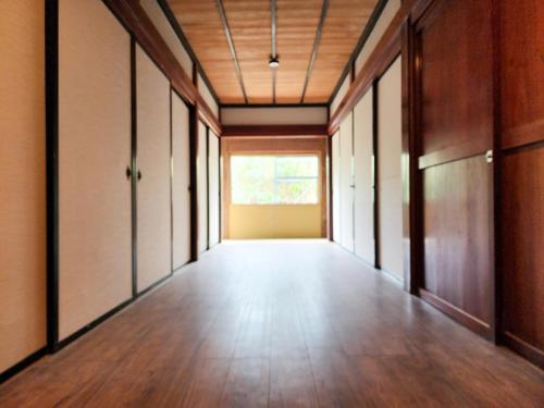 an empty hallway with wood floors and a window at タイピーハウス in Sado
