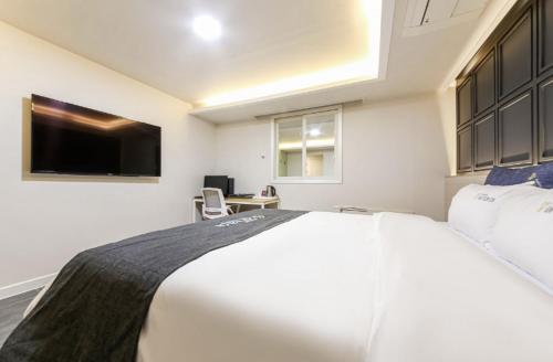 a bedroom with a large white bed and a desk at Gwangju Yeogijoa Hotel in Gwangju