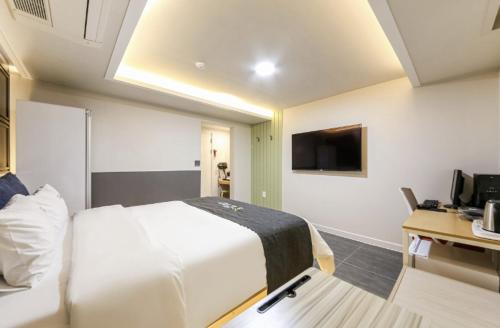 a hotel room with a white bed and a television at Gwangju Yeogijoa Hotel in Gwangju