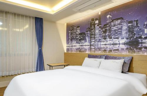 a bedroom with a white bed and a painting on the wall at Gwangju Yeogijoa Hotel in Gwangju