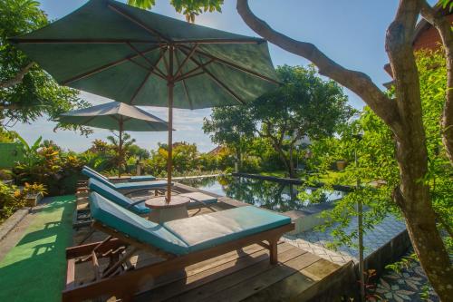 a patio with an umbrella and chairs and a pool at Govardhan Nusa Penida in Nusa Penida