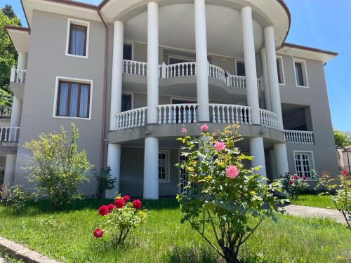 a large white house with flowers in the yard at Villa Baqs in Racha in Ambrolauri