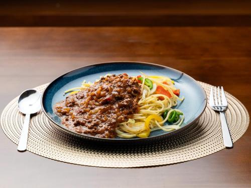 a plate of pasta with meat and vegetables on a table at ホテルオアシスガーデン in Obita