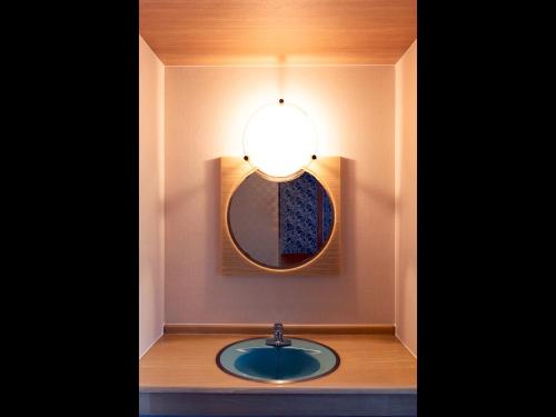 a bathroom with a sink with a mirror and a light at ホテルオアシスガーデン in Obita