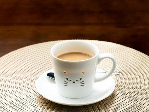 a cup of coffee sitting on a plate on a table at ホテルオアシスガーデン in Obita