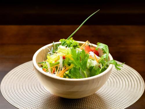 a salad in a white bowl on a table at ホテルオアシスガーデン in Obita