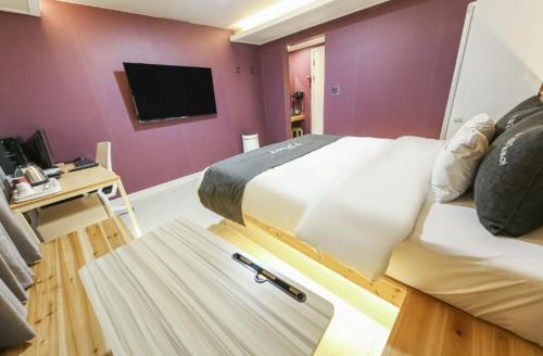 a bedroom with a large bed and a tv at Gwangju Yeogijoa Hotel in Gwangju