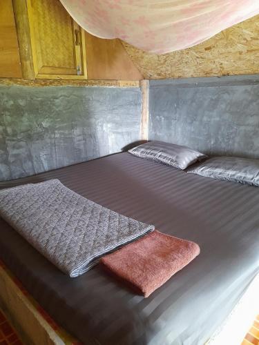 a bed with two pillows on it in a room at KK Hut in Pai