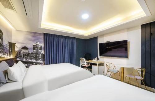 a hotel room with a white bed and a desk at Gwangju Yeogijoa Hotel in Gwangju